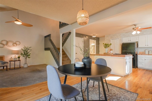 dining space with a textured ceiling, light wood-type flooring, and ceiling fan