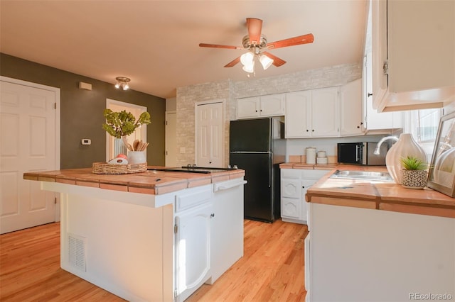 kitchen with a kitchen island, white cabinetry, light wood-type flooring, and black fridge