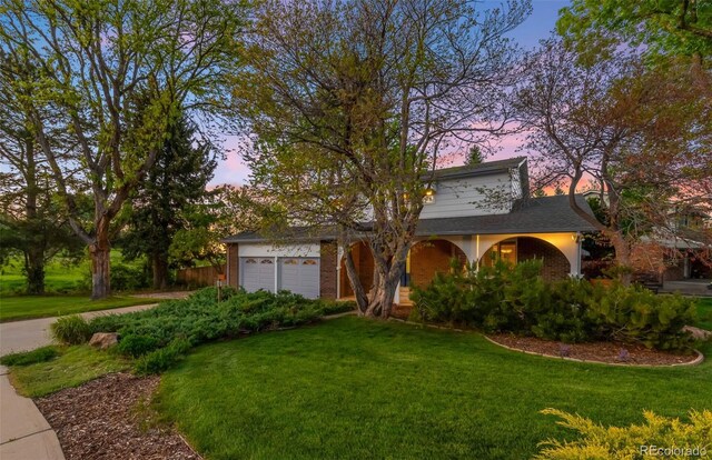9765 W 77th Dr, Arvada, CO 80005 - view of front of home featuring a lawn, a garage, covered porch, and brick siding