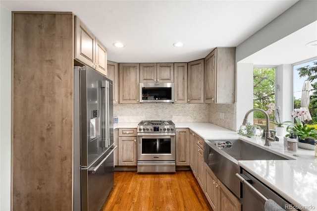 9765 W 77th Dr, Arvada, CO 80005 - kitchen featuring stainless steel appliances, light countertops, a sink, backsplash, and light wood-style floors