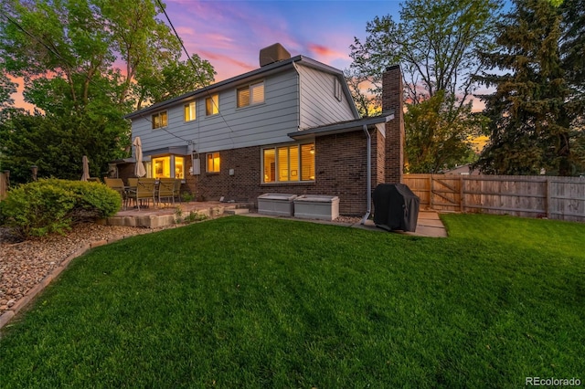 9765 W 77th Dr, Arvada, CO 80005 - back of property featuring a chimney, a jacuzzi, brick siding, and a patio area