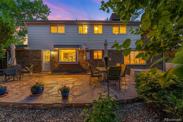 9765 W 77th Dr, Arvada, CO 80005 - back of property at dusk with a patio and brick siding