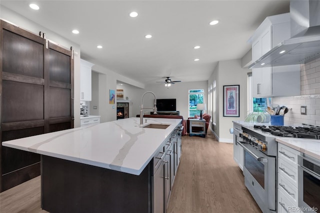 16079 Red Fox Ln, Colorado Springs, CO 80921 - kitchen with high end stainless steel range oven, wall chimney exhaust hood, a fireplace, a sink, and open floor plan