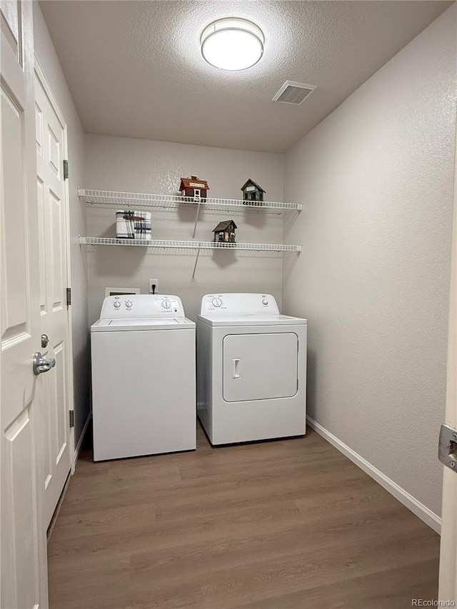 10676 Forester Pl, Longmont, CO 80504 - washroom with separate washer and dryer, a textured ceiling, wood finished floors, and baseboards