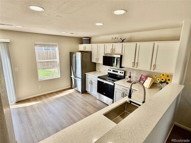 10676 Forester Pl, Longmont, CO 80504 - kitchen with appliances with stainless steel finishes, a sink, white cabinets, recessed lighting, and a textured ceiling