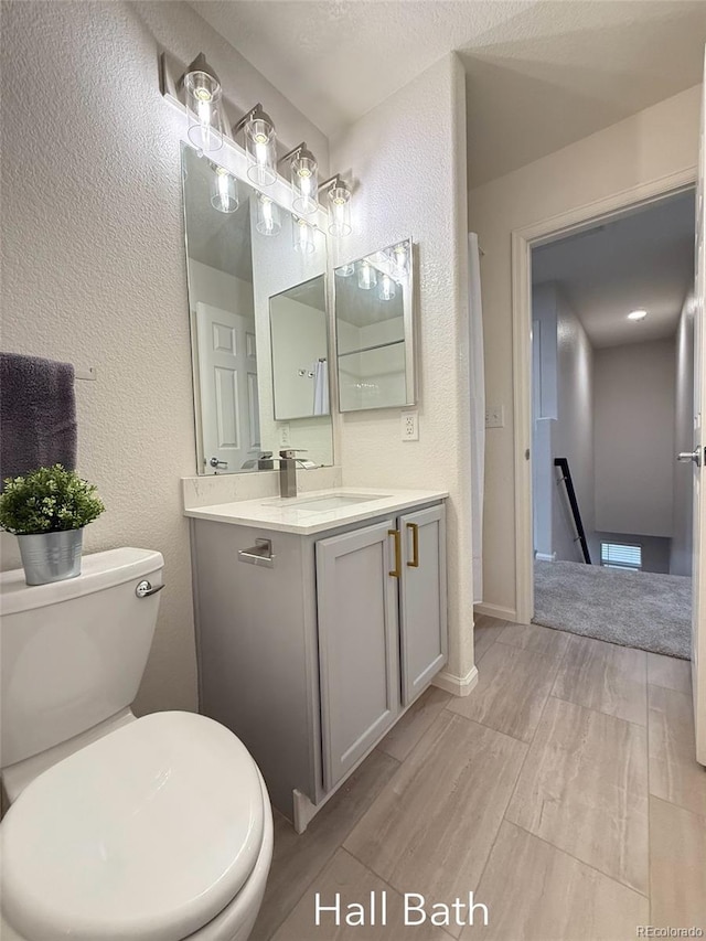 10676 Forester Pl, Longmont, CO 80504 - bathroom featuring vanity, wood finished floors, a textured wall, toilet, and baseboards