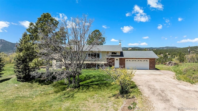 19260 Spring Valley Rd, Monument, CO 80132 - view of front of house with driveway, a mountain view, an attached garage, and brick siding