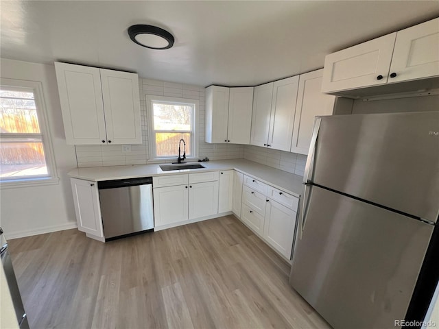 kitchen with decorative backsplash, white cabinetry, sink, and appliances with stainless steel finishes