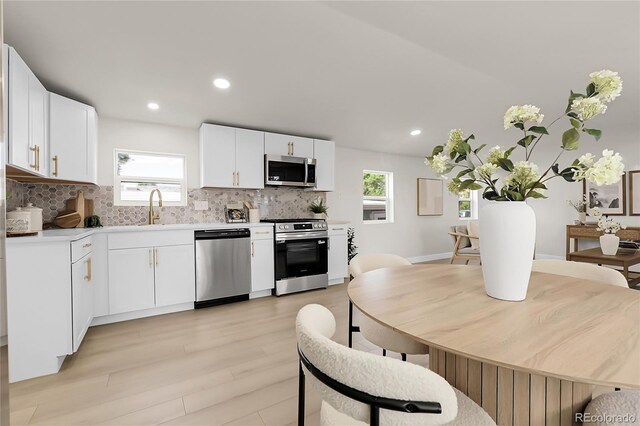 8497 Madison Way, Denver, CO 80229 - kitchen with appliances with stainless steel finishes, a sink, decorative backsplash, light wood-type flooring, and plenty of natural light