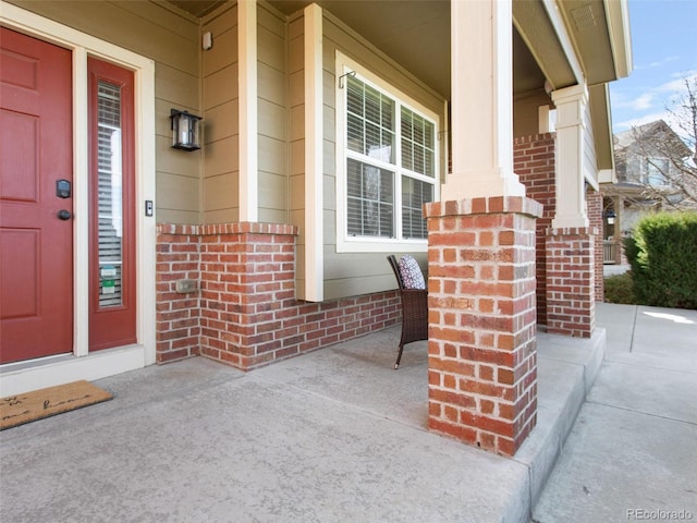 entrance to property featuring brick siding and a porch