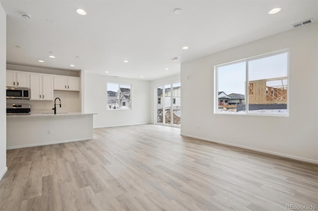 unfurnished living room featuring light wood-type flooring, visible vents, baseboards, and recessed lighting