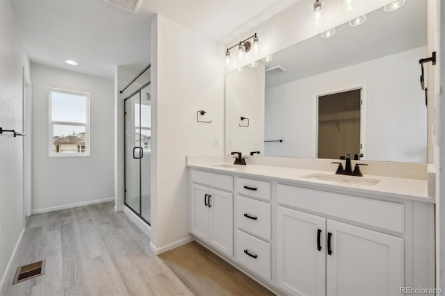 bathroom with visible vents, a sink, a shower stall, and double vanity