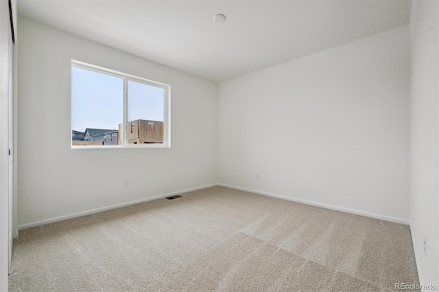 carpeted spare room with visible vents and baseboards