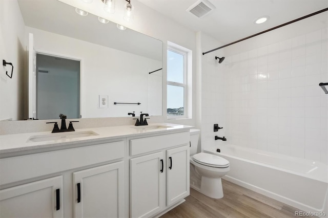 bathroom featuring shower / bathtub combination, visible vents, a sink, and wood finished floors