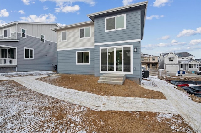 snow covered house with entry steps, a residential view, and central AC unit