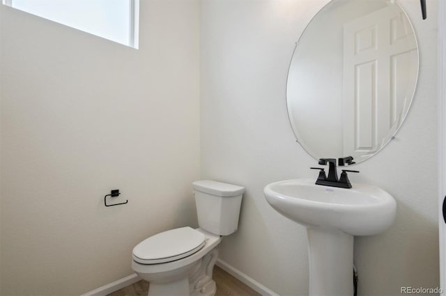 bathroom with baseboards, toilet, and wood finished floors