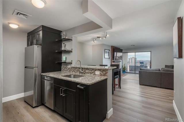 kitchen with visible vents, a sink, open shelves, dark cabinetry, and appliances with stainless steel finishes