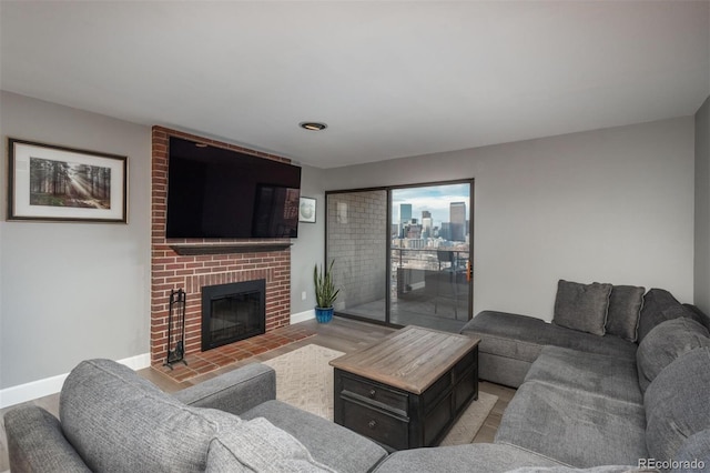 living area featuring baseboards, a brick fireplace, and light wood-style flooring