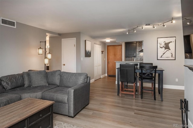 living room featuring baseboards, visible vents, and light wood finished floors