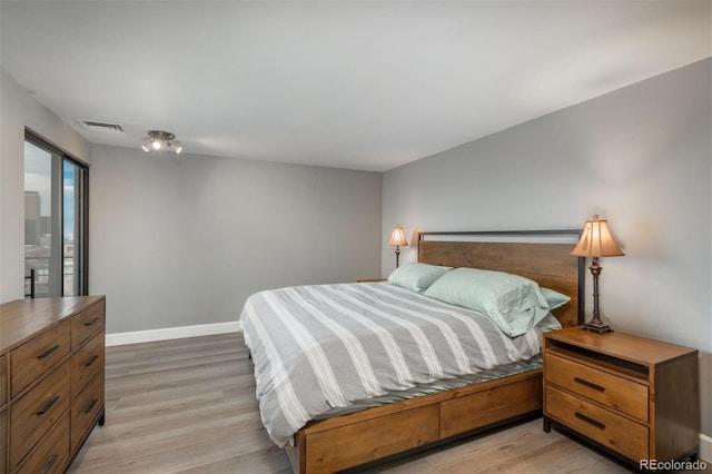 bedroom featuring light wood-style floors, visible vents, and baseboards