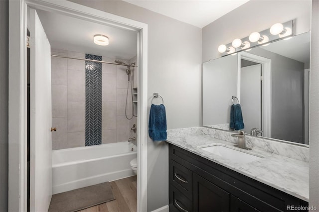 bathroom featuring toilet, wood finished floors, vanity, and shower / tub combination
