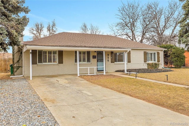 ranch-style home featuring brick siding, a porch, a shingled roof, and a front yard