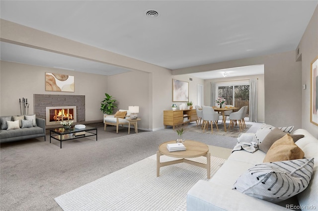 carpeted living room with a glass covered fireplace, visible vents, and baseboards