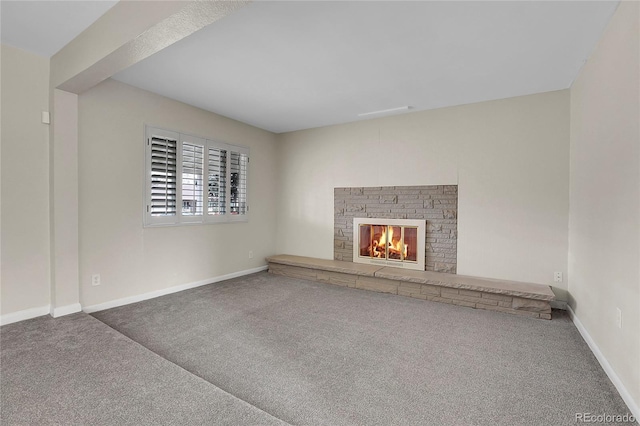 unfurnished living room featuring carpet, a fireplace, and baseboards