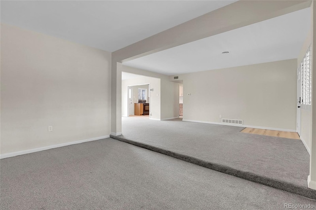 spare room featuring carpet floors, visible vents, and baseboards