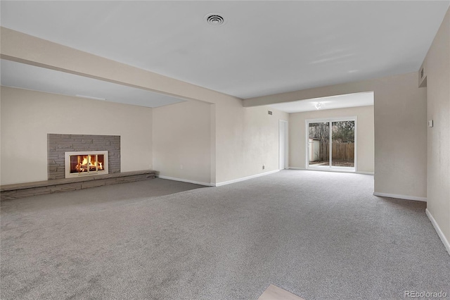 unfurnished living room with carpet, a fireplace, visible vents, and baseboards