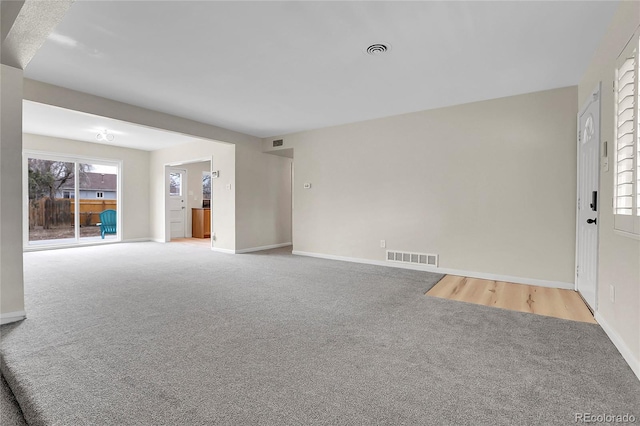 unfurnished living room featuring light carpet, visible vents, and baseboards