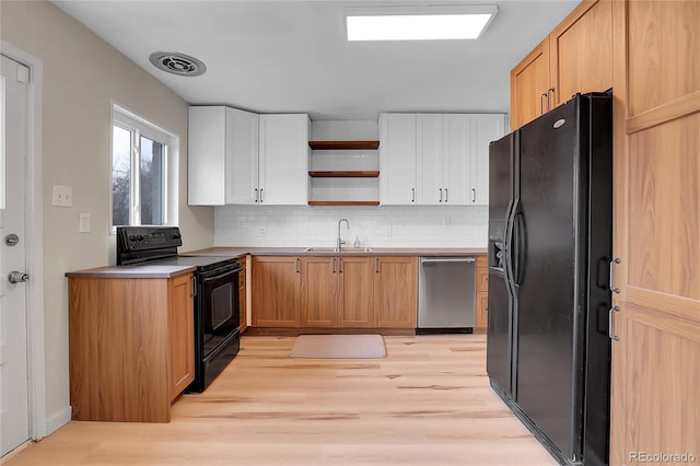 kitchen with white cabinets, light countertops, black appliances, open shelves, and a sink