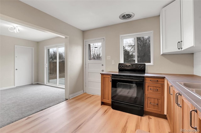 kitchen featuring plenty of natural light, visible vents, brown cabinetry, white cabinets, and black range with electric stovetop