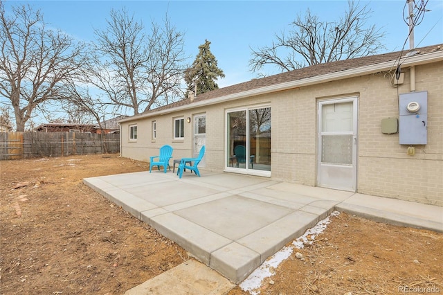 rear view of house featuring a patio area, fence, and brick siding