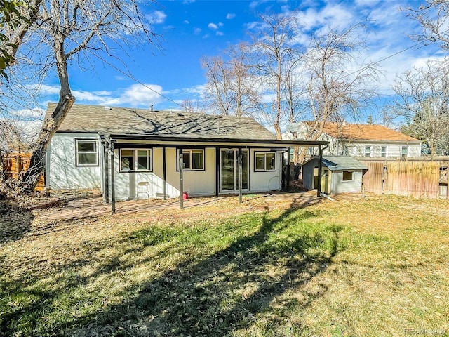 rear view of property with a storage shed and a lawn