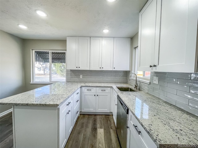 kitchen with sink, white cabinets, dark hardwood / wood-style flooring, stainless steel dishwasher, and light stone counters