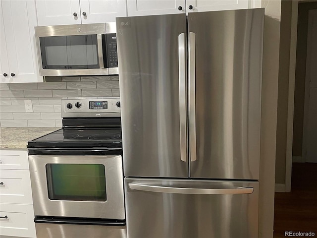 kitchen featuring stainless steel appliances, white cabinetry, tasteful backsplash, and light stone counters