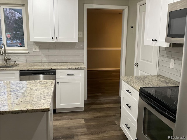 kitchen with stainless steel appliances, dark wood-type flooring, white cabinets, and light stone counters