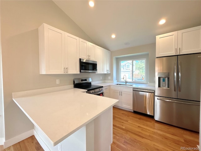 kitchen featuring stainless steel appliances, lofted ceiling, kitchen peninsula, and sink