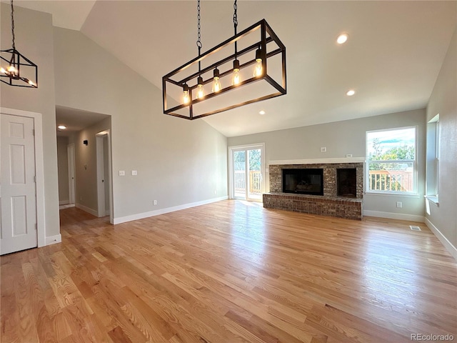 unfurnished living room with high vaulted ceiling, light wood-type flooring, and a fireplace