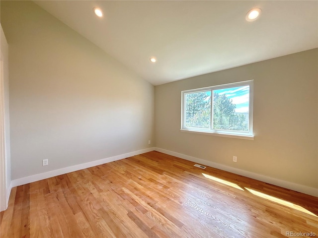 empty room with vaulted ceiling and light hardwood / wood-style floors