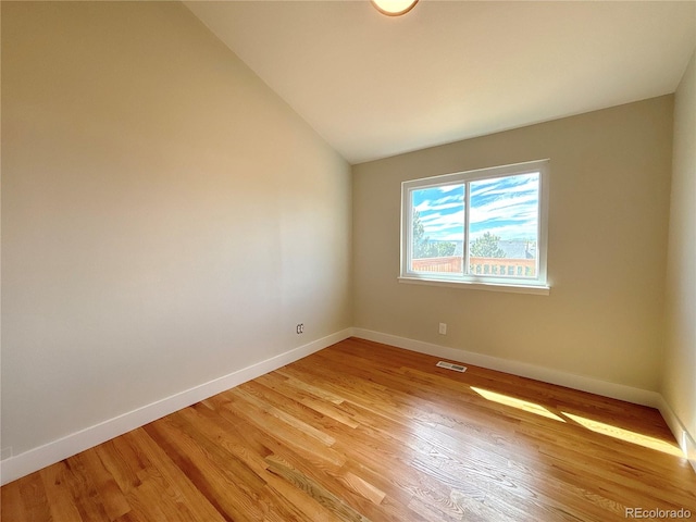 spare room with light hardwood / wood-style flooring and lofted ceiling