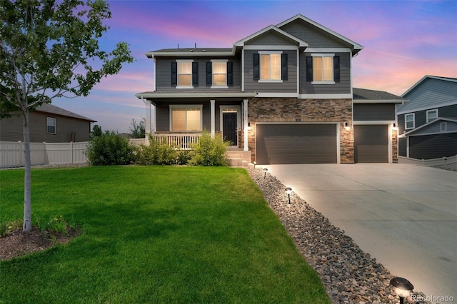 craftsman-style home featuring covered porch, fence, a yard, stone siding, and driveway