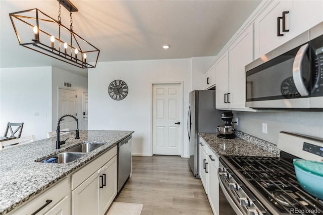 kitchen featuring stainless steel appliances, light wood finished floors, a sink, and white cabinets