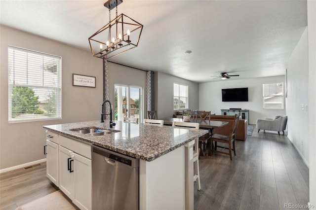 kitchen with light wood-style floors, a center island with sink, a sink, and stainless steel dishwasher