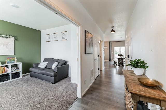 hall with visible vents, baseboards, and wood finished floors