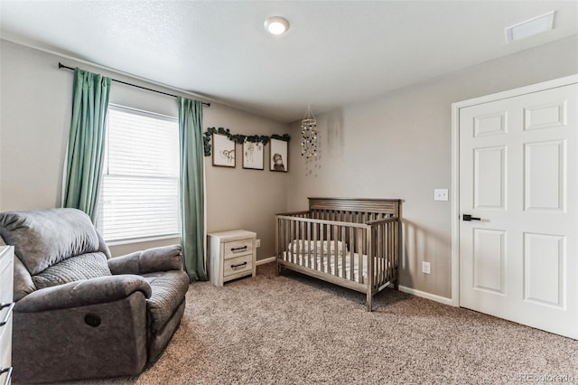 bedroom featuring a nursery area, carpet flooring, visible vents, and baseboards