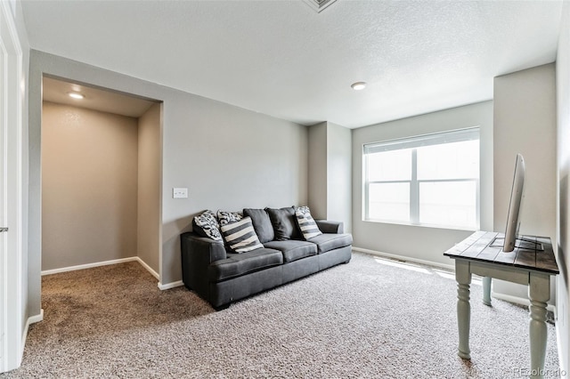 carpeted living room with a textured ceiling and baseboards