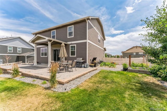 rear view of house with a patio area, a garden, fence, and a lawn