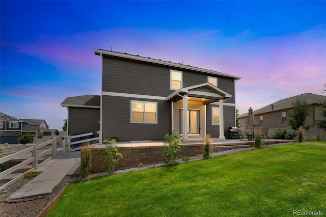 traditional home featuring a patio, fence, and a lawn